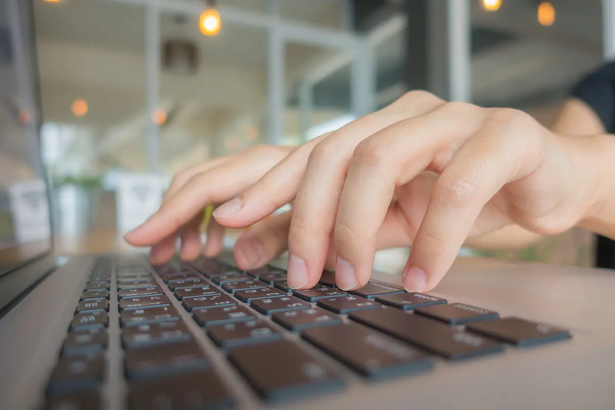 Eine Person tippt auf der Tastatur eines Laptops