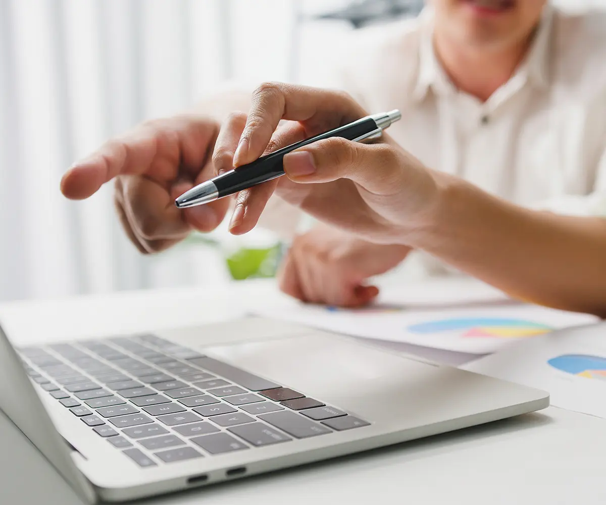 Ein Mann zeigt mit einem Stift auf den Bildschirm seines Laptops