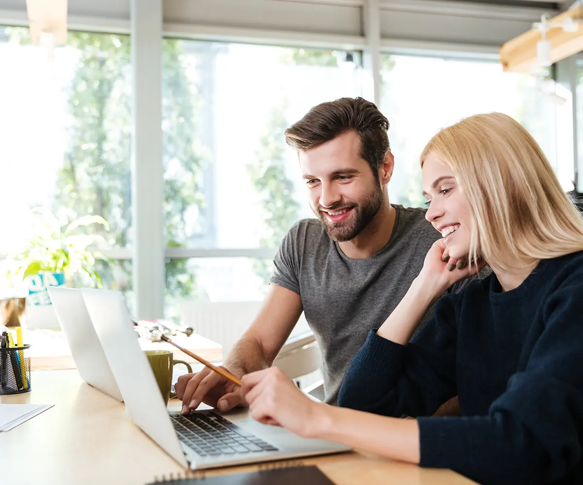 Ein Mann und eine Frau sitzen an einem Tisch mit einem Laptop und diskutieren.